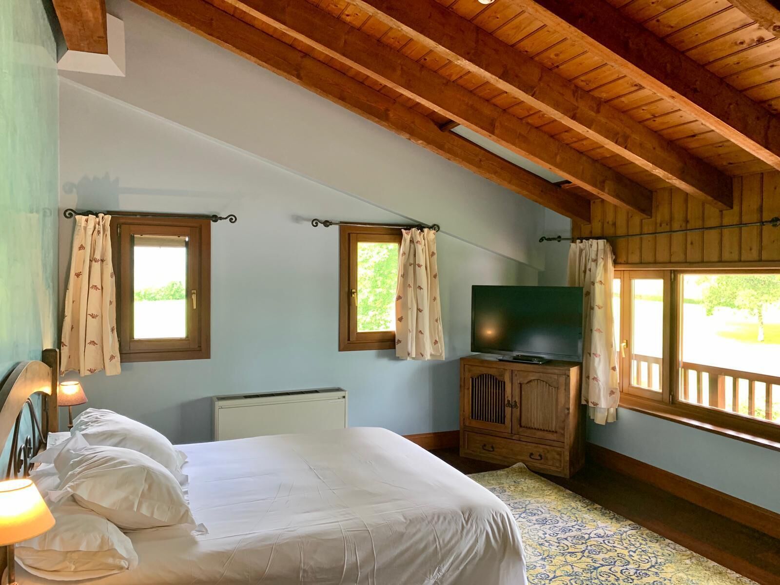 Un dormitorio con cama, televisor y aparador de madera.