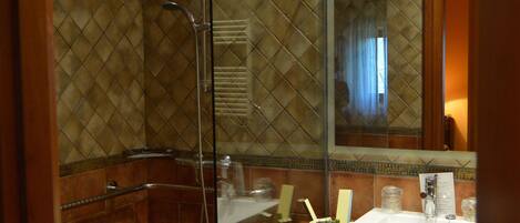 Une salle de bain avec une douche à parois de verre, un lavabo avec des articles de toilette et un miroir qui reflète la pièce.