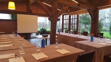 Una sala de conferències amb taules llargues, cadires i una pantalla de projector.