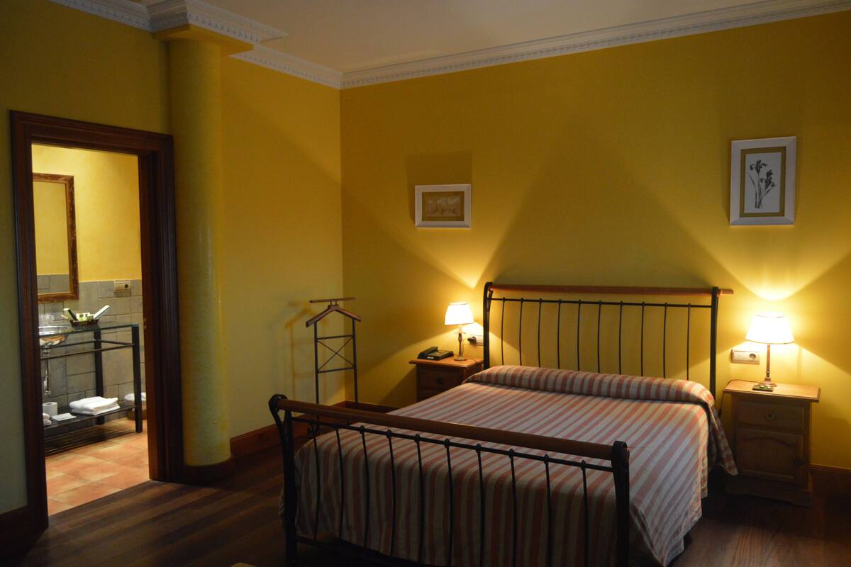 A hotel room with a bed, two bedside tables with lamps, a mirror, and a framed picture on the wall.