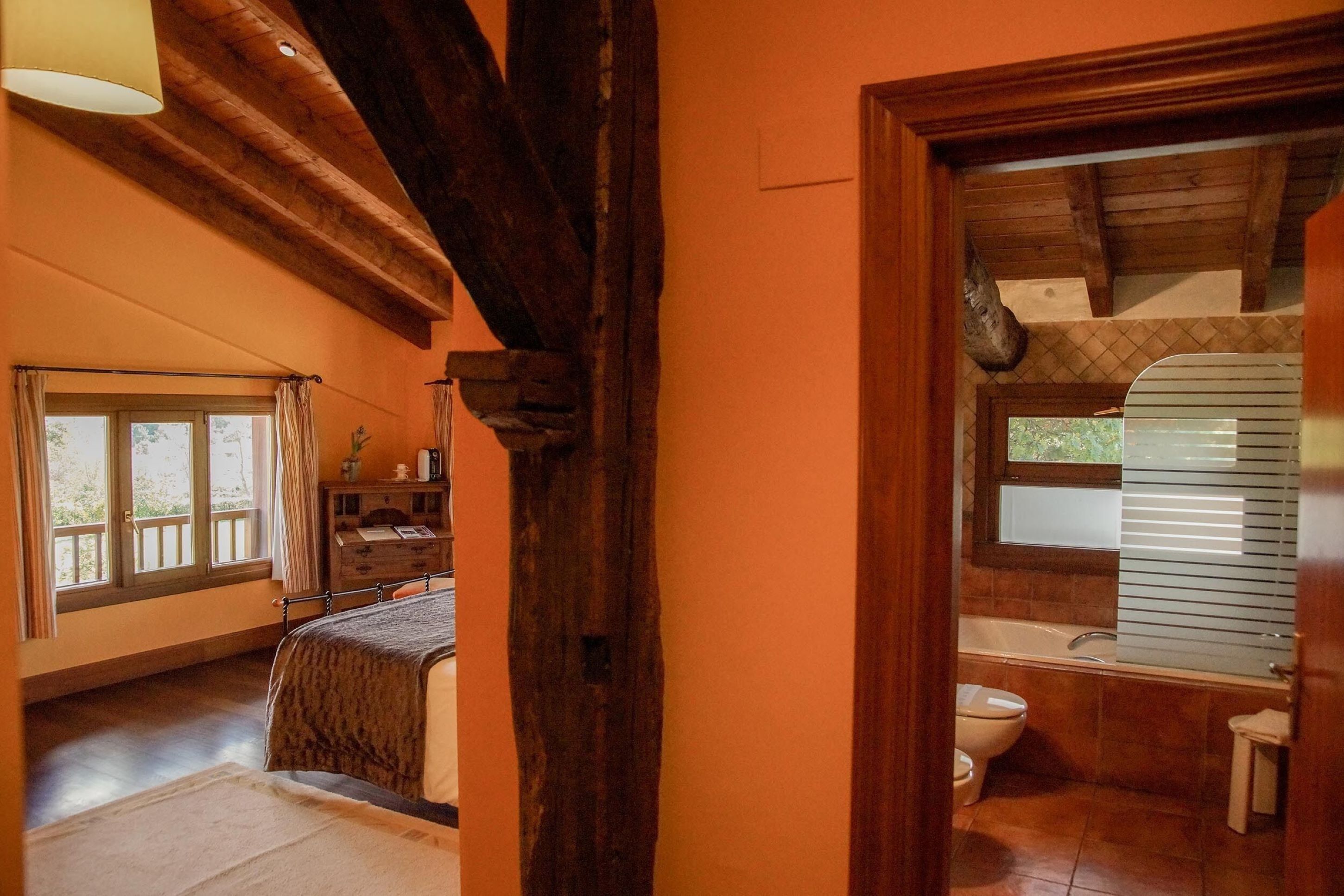 A bedroom with a large window, a wooden ceiling, and a view of the outdoors.