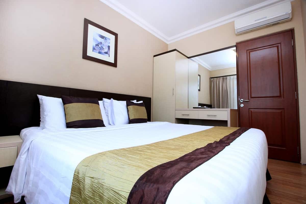 A hotel room with a bed, a nightstand, a dresser, a mirror, and a door.