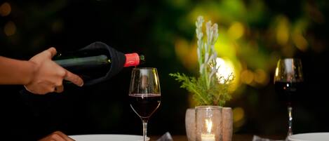 A dining table with two wine glasses, a candle, and a potted plant.