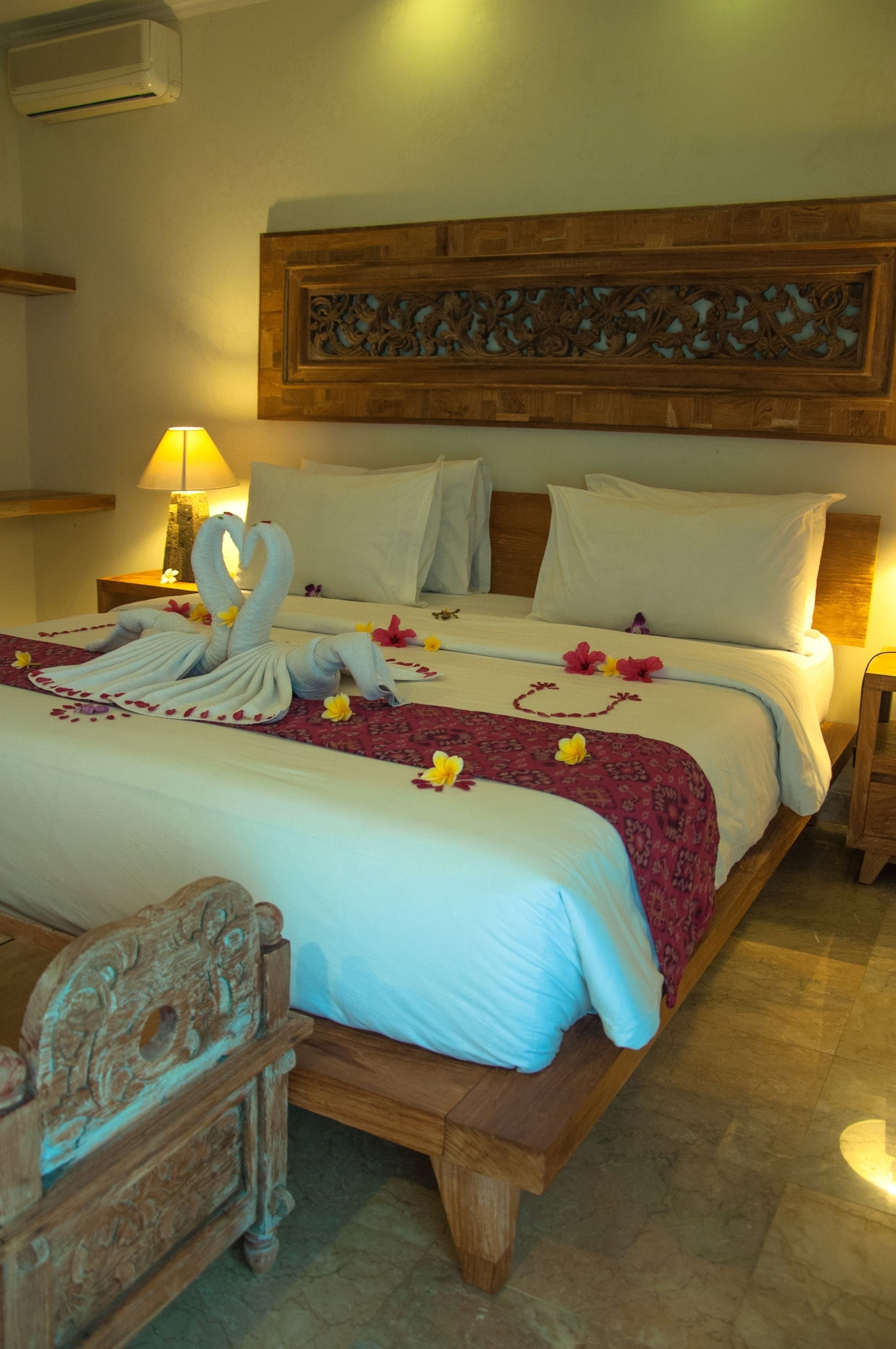 Una habitación de hotel con una cama, cabecera de madera y una mesita de noche con lámpara.