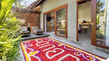 A modern house with a patio area featuring a colorful flower carpet, outdoor seating, and a view of the interior.