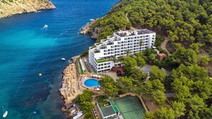 An aerial view of a coastal hotel with a swimming pool, tennis court, and a view of the sea. - Palladium Hotel Cala Llonga - Adults Only (Santa Eulalia del Rio)