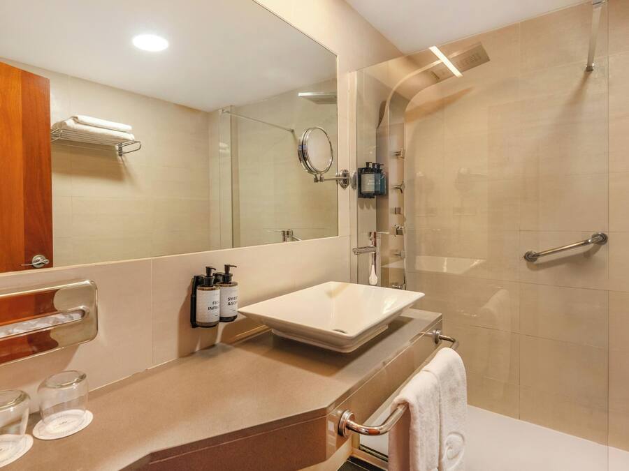 Un baño moderno con un espejo grande, un lavamanos y una zona de ducha.