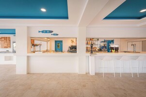 Zona de bar con mostrador, taburetes y techo azul.