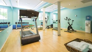 Un gimnasio con equipo de ejercicio, dispensador de agua y pared de espejos.
