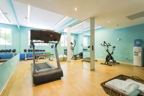 A gym with exercise equipment, a water dispenser, and a mirror wall. - Palladium Hotel Cala Llonga - Adults Only (Santa Eulalia del Rio)