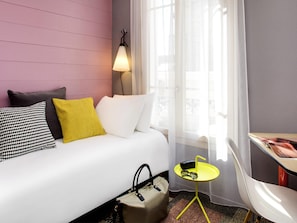 Une chambre d’hôtel avec un lit, une lampe de chevet, une petite table avec des verres et une chaise.