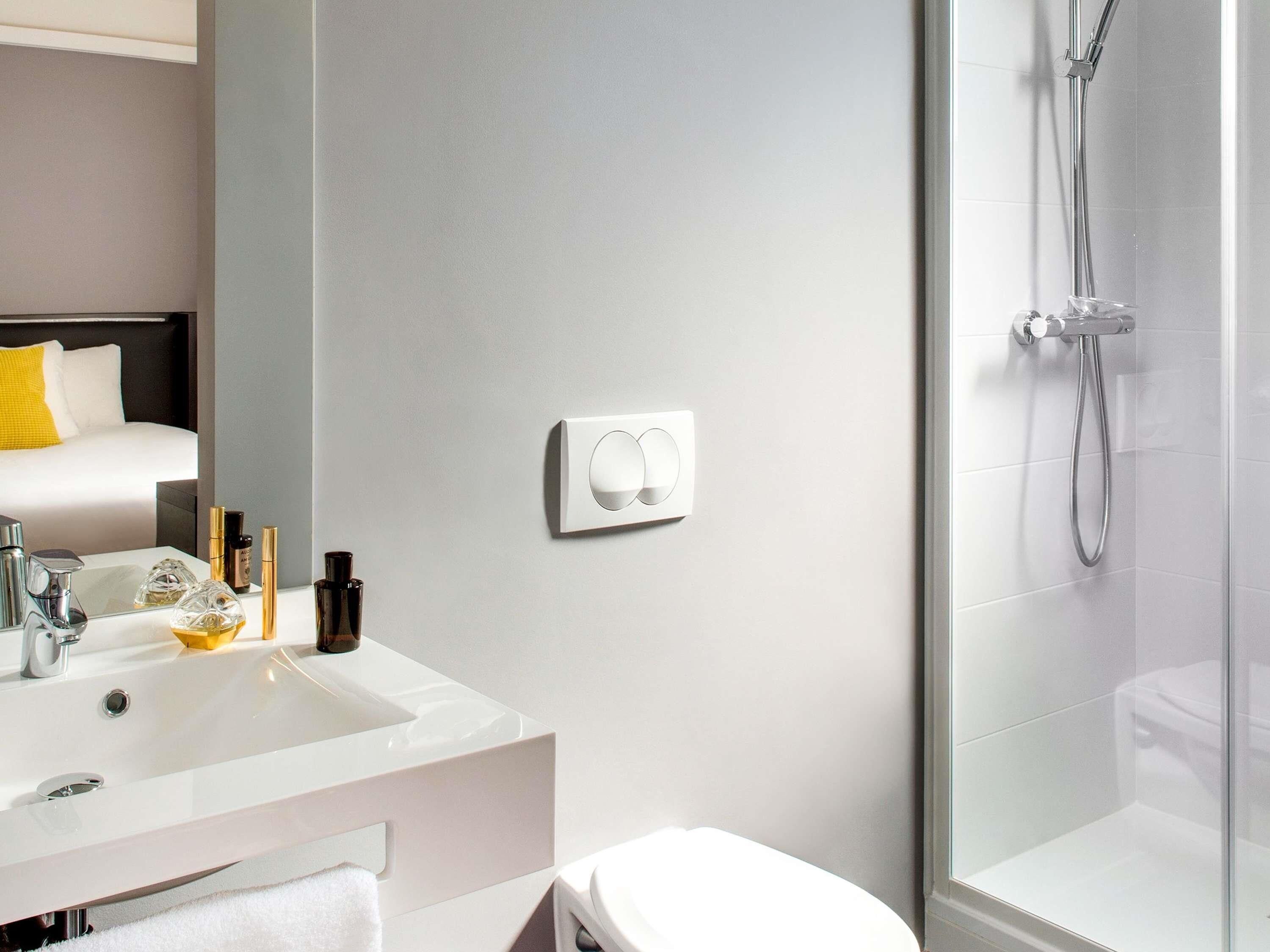 Ein modernes Badezimmer mit einem weißen Waschbecken, Spiegel und WC.