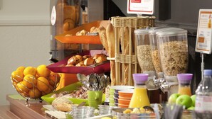 Un bufé de desayuno con diversas opciones de comida e iluminado por vistosas lámparas colgantes.