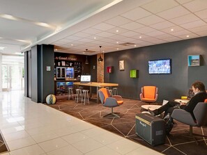 Un espace de détente moderne doté d’un bar, de sièges et d’un écran de télévision.
