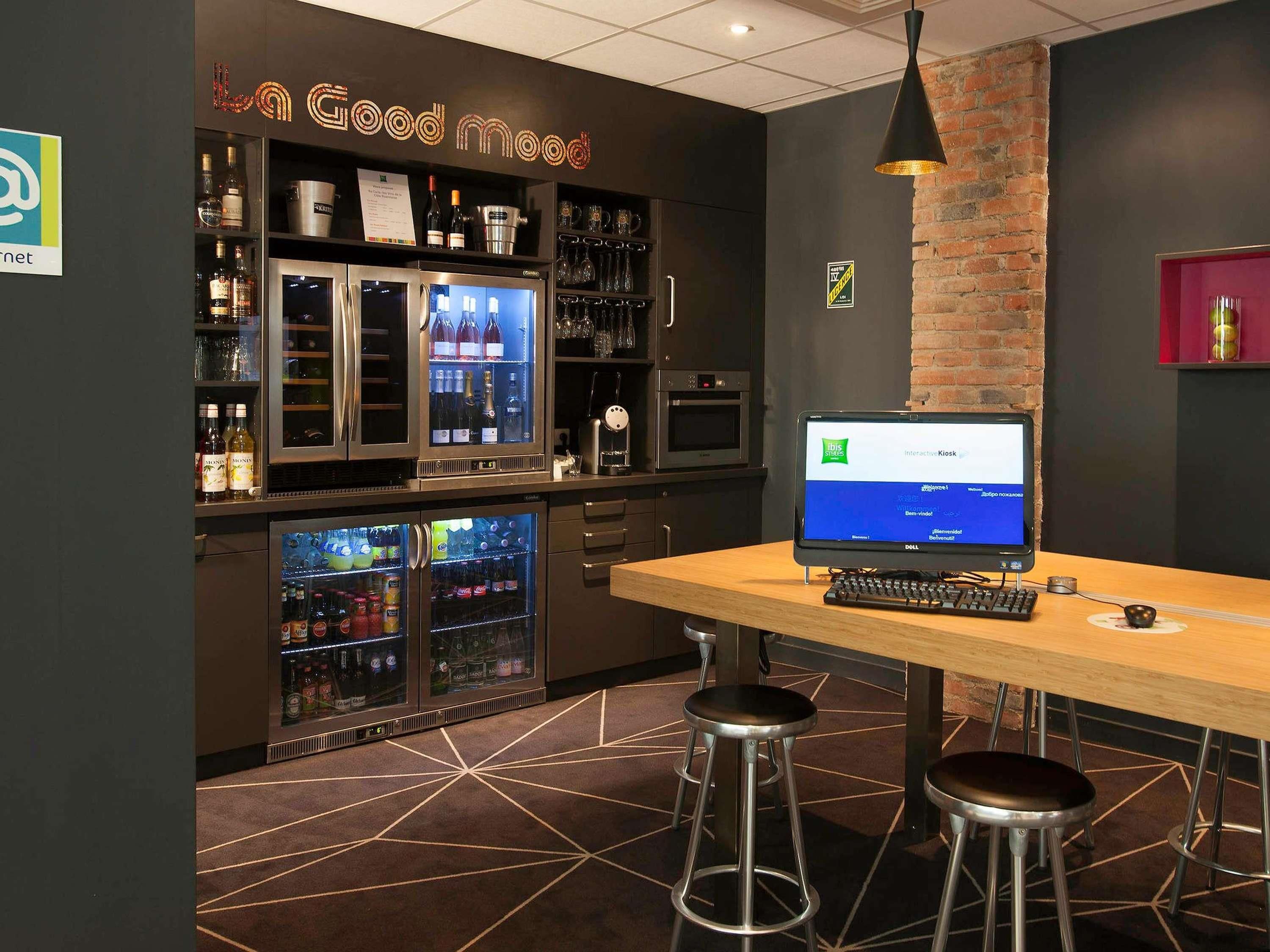 A bar area with a computer monitor, stools, and shelves stocked with bottles.