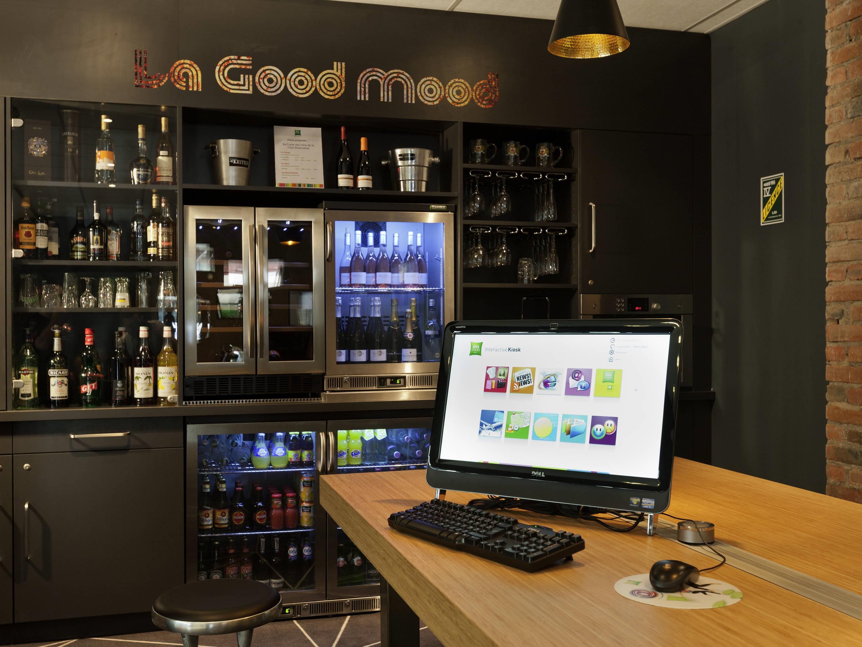 A bar area with a computer monitor displaying various apps, a keyboard, and a mouse on a wooden table.