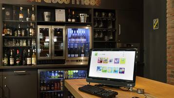 A bar area with a computer monitor displaying various apps, a keyboard, and a mouse on a wooden table.