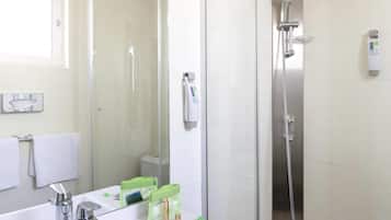A modern bathroom with a glass-enclosed shower, a white sink with a mirror, and a towel rack.