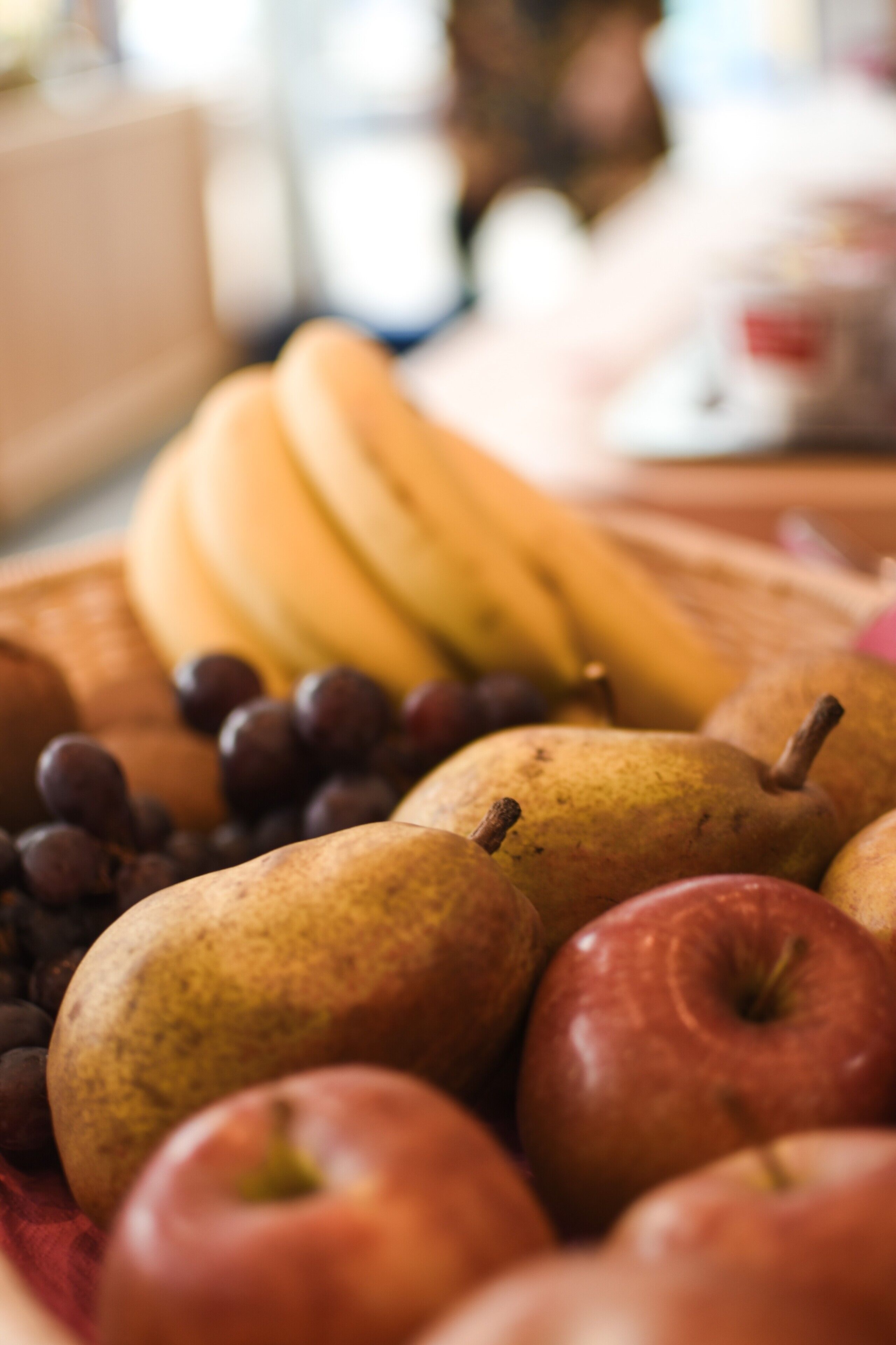 Een close-up van een fruitplateau met bananen, druiven, peren en appels.