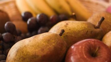 Een close-up van een fruitplateau met bananen, druiven, peren en appels.