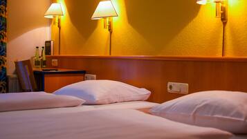 A hotel room with two beds, a nightstand, and two wall-mounted lamps.