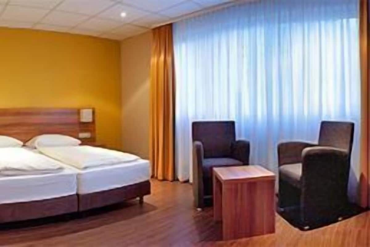 A hotel room with a bed, a sofa, a desk, and a chair.