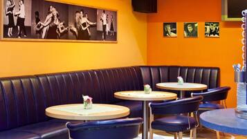 A restaurant with a booth seating area, round tables, and black leather booths.