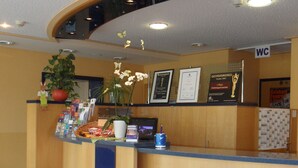 A reception desk with a plant, framed certificates, and a WC sign.