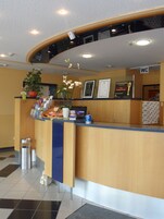 Un mostrador de recepción con una planta, diplomas enmarcados y un letrero de baño.