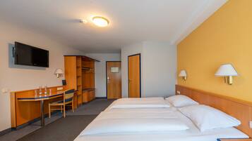 A hotel room with a bed, a desk, a chair, a television, and a wardrobe.