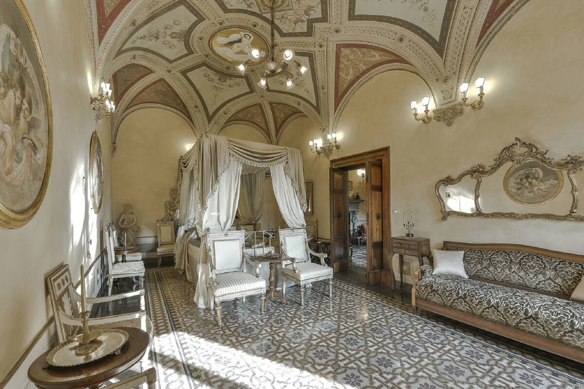 A luxurious bedroom with a canopy bed, ornate ceiling, and classic furniture.