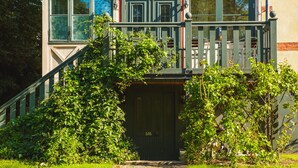 A two-story building with a green front door, a visible number '505', and a small porch with a railing. - Hotell Breda Blick (Visby)