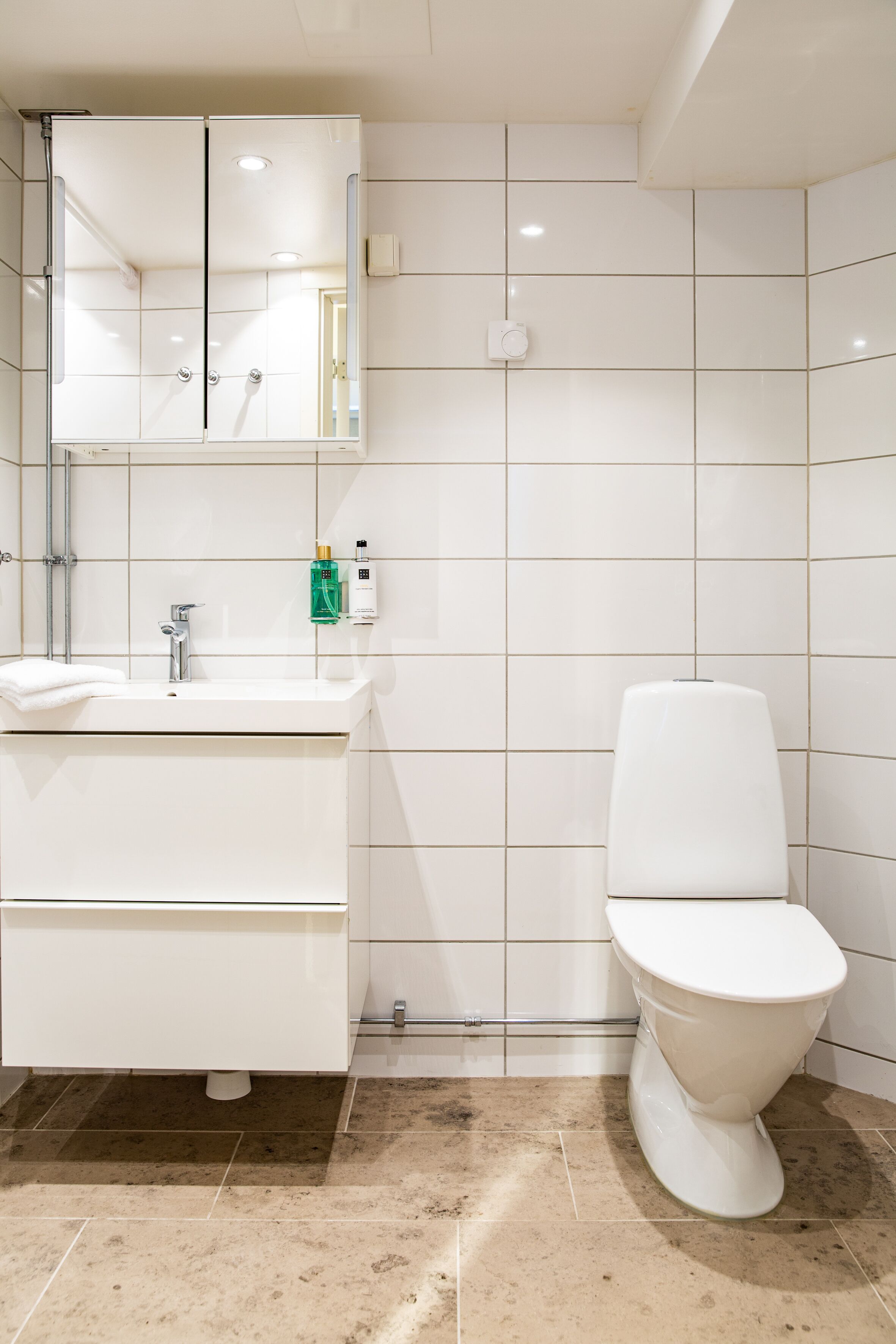 A modern bathroom with a white sink, mirror, and toilet.