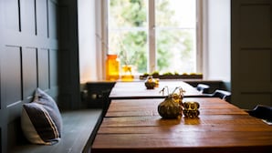 A wooden table with a vase and candle in a room with a window and a bench. - Hotell Breda Blick (Visby)