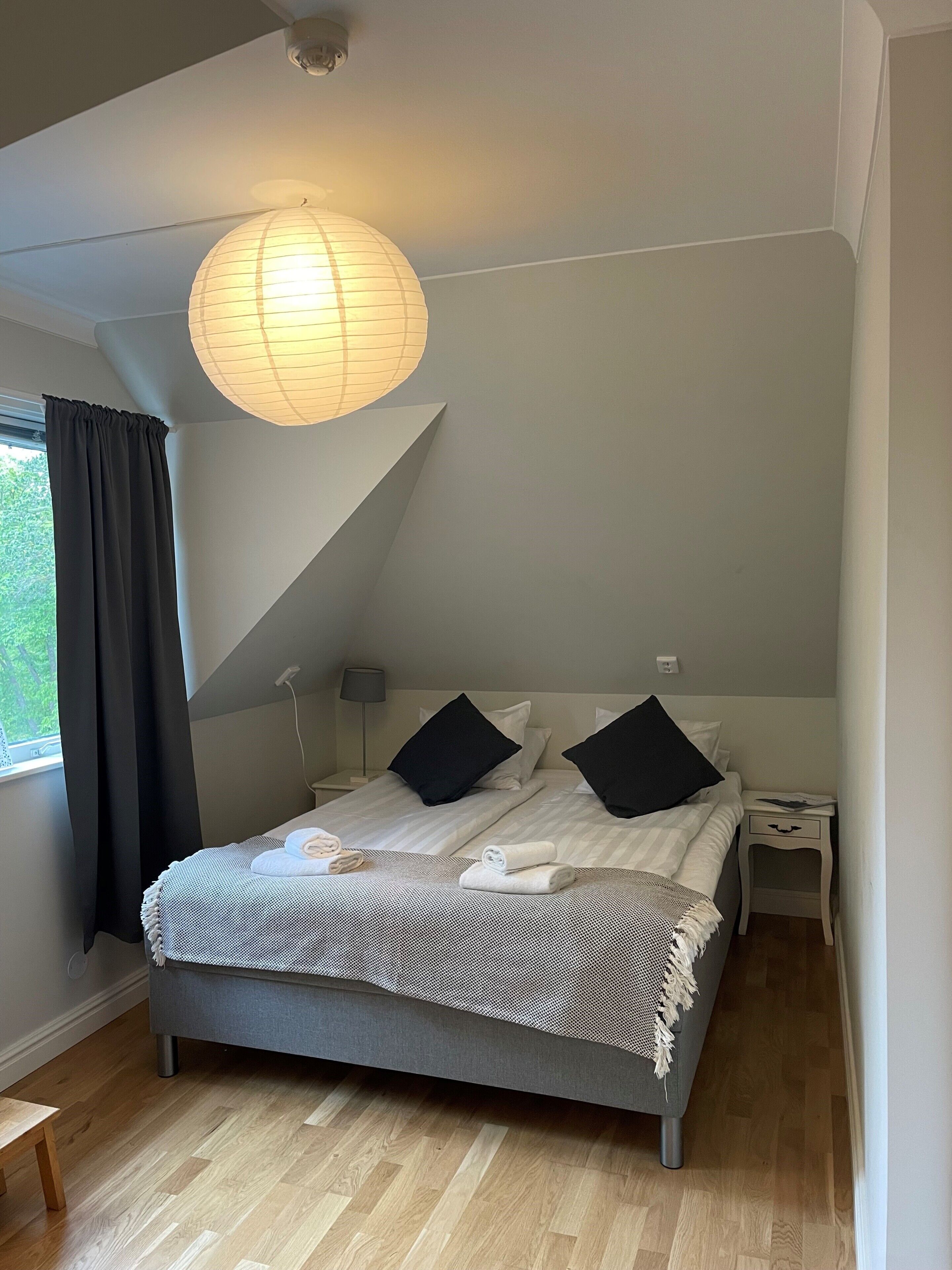 A bedroom with a bed, a nightstand, a lamp, and a ceiling light fixture.