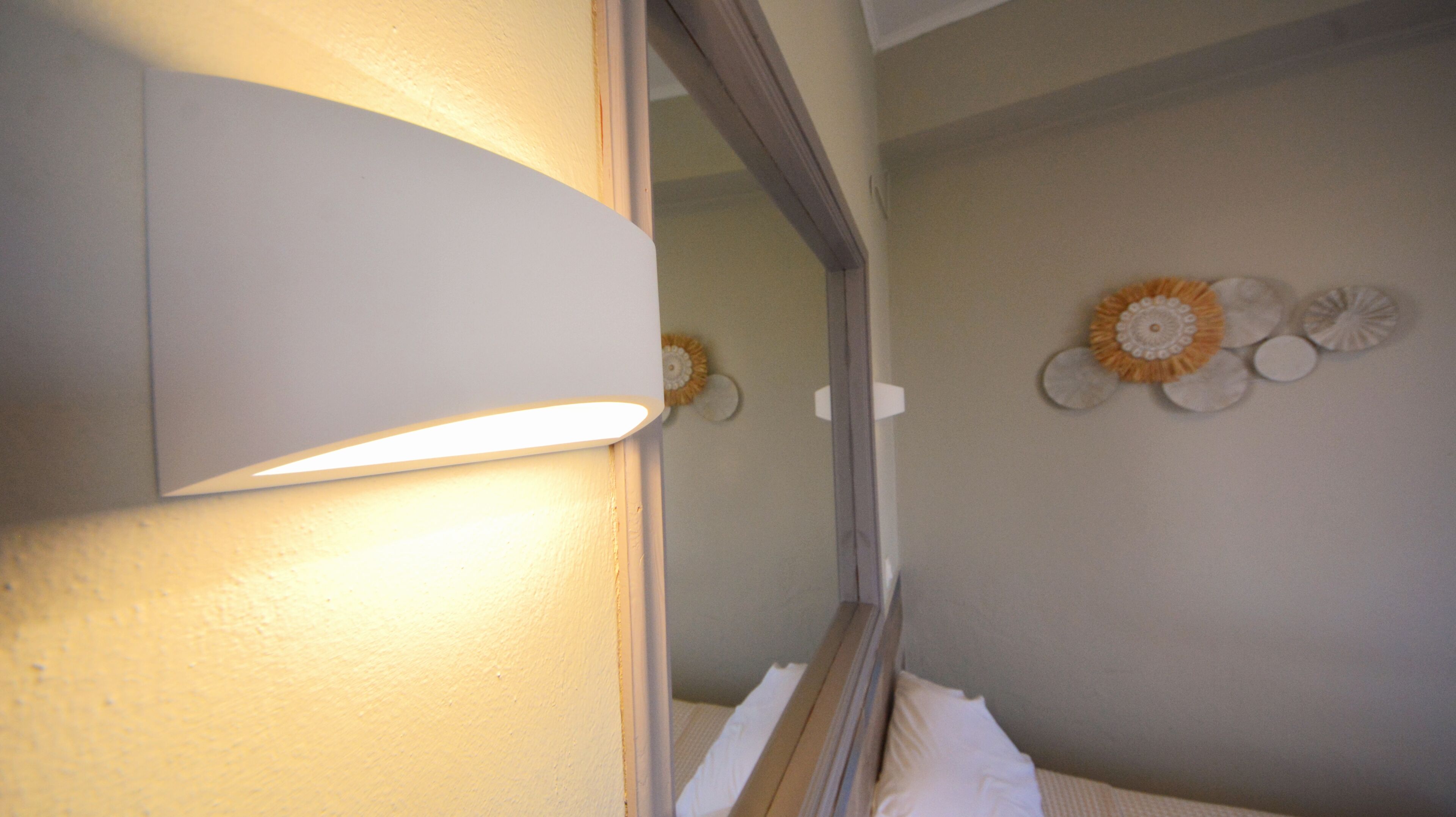 Un baño con espejo, luz empotrada en la pared y un elemento decorativo.