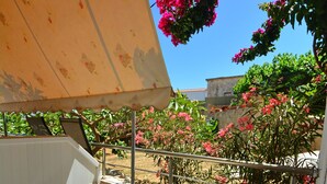 A patio with a stone wall, a metal railing, and a plastic chair. - Family Bikakis (Kissamos)