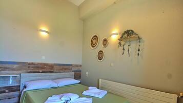 A room with two beds, a ceiling light, wall-mounted sconces, and a decorative wall hanging.