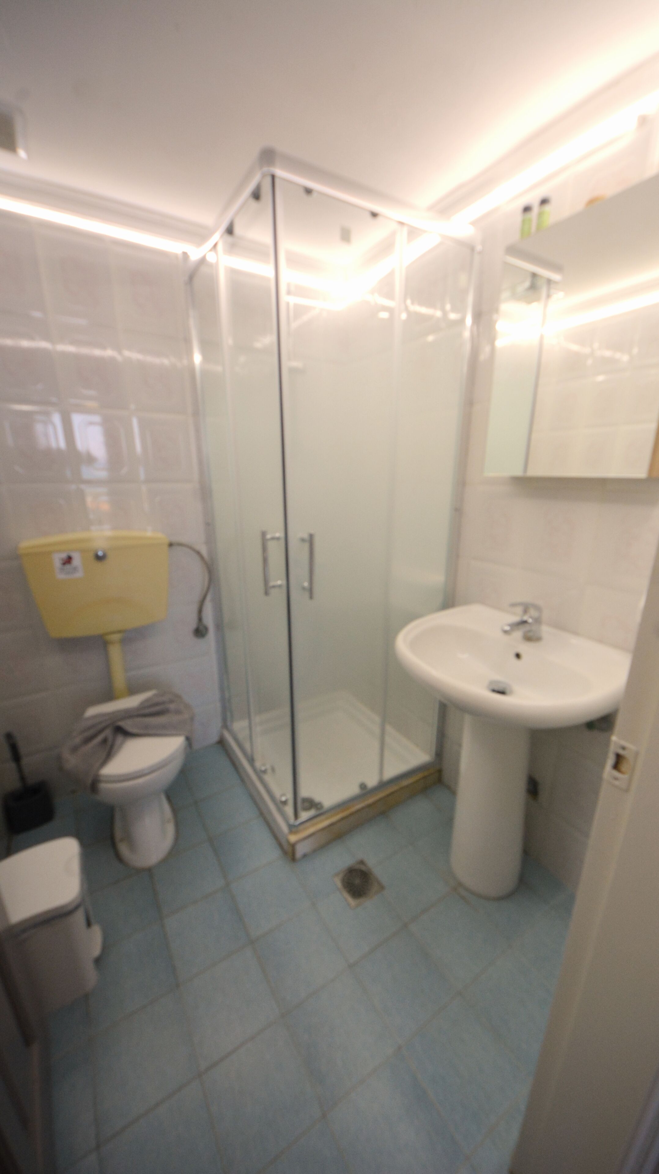 A bathroom with a glass-enclosed shower, a toilet, and a sink.