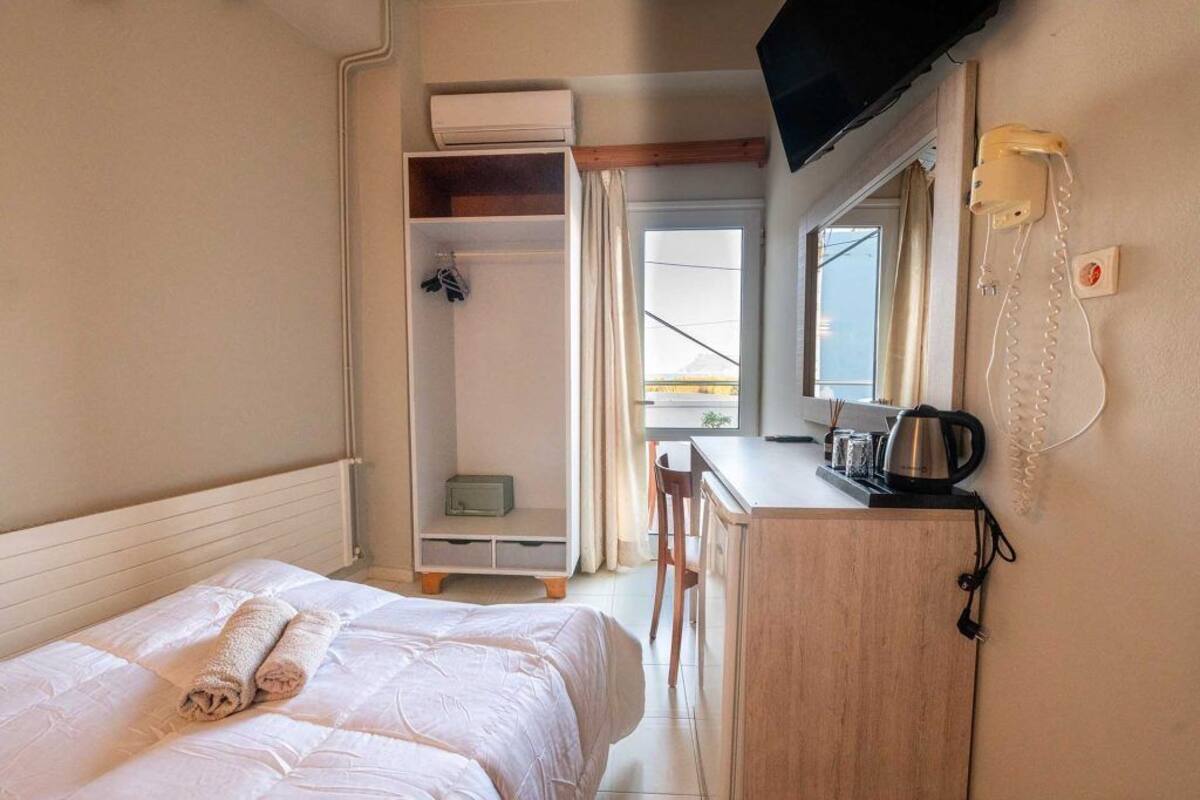 A hotel room with a bed, a desk, a chair, a wardrobe, a television, and a telephone.