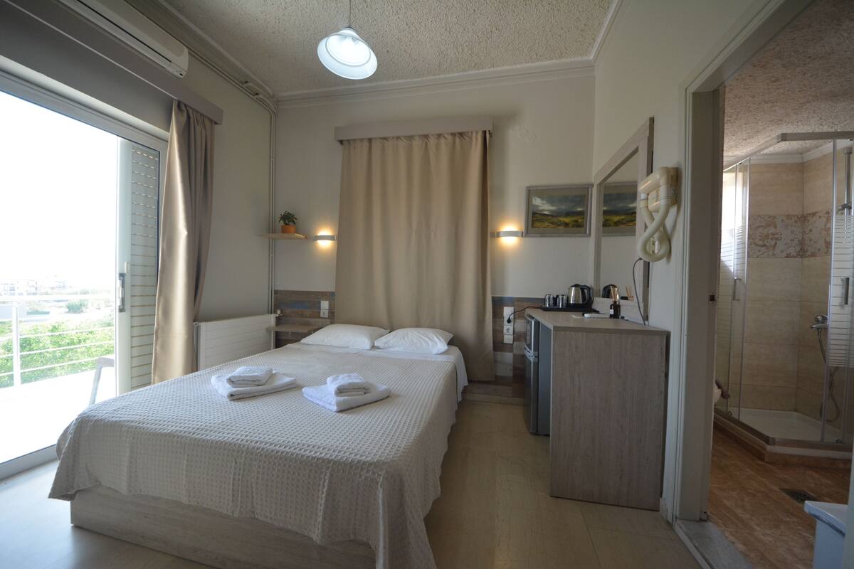 A hotel room with a bed, a desk, a shower, and a view of the city.