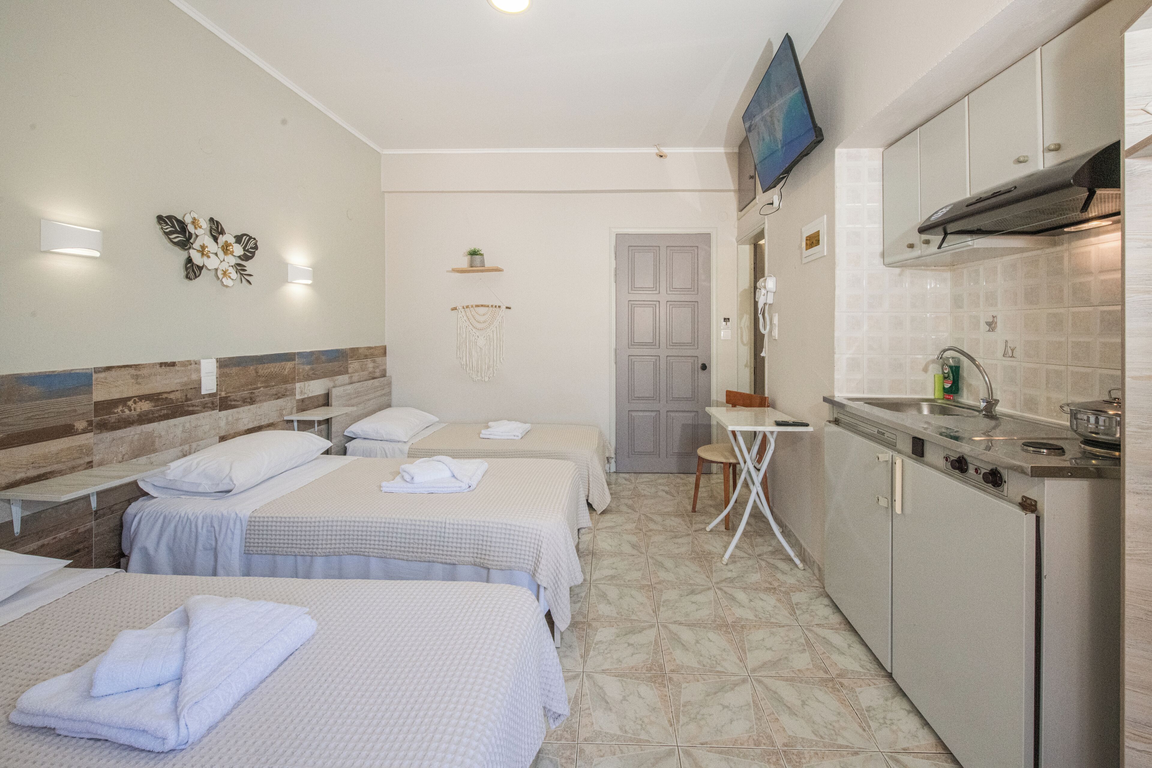 Una camera d'albergo con due letti, angolo cottura e bagno.