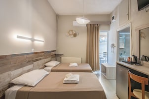 Habitación de hotel con dos camas, un pequeño rincón americano, un espejo y vistas al exterior.