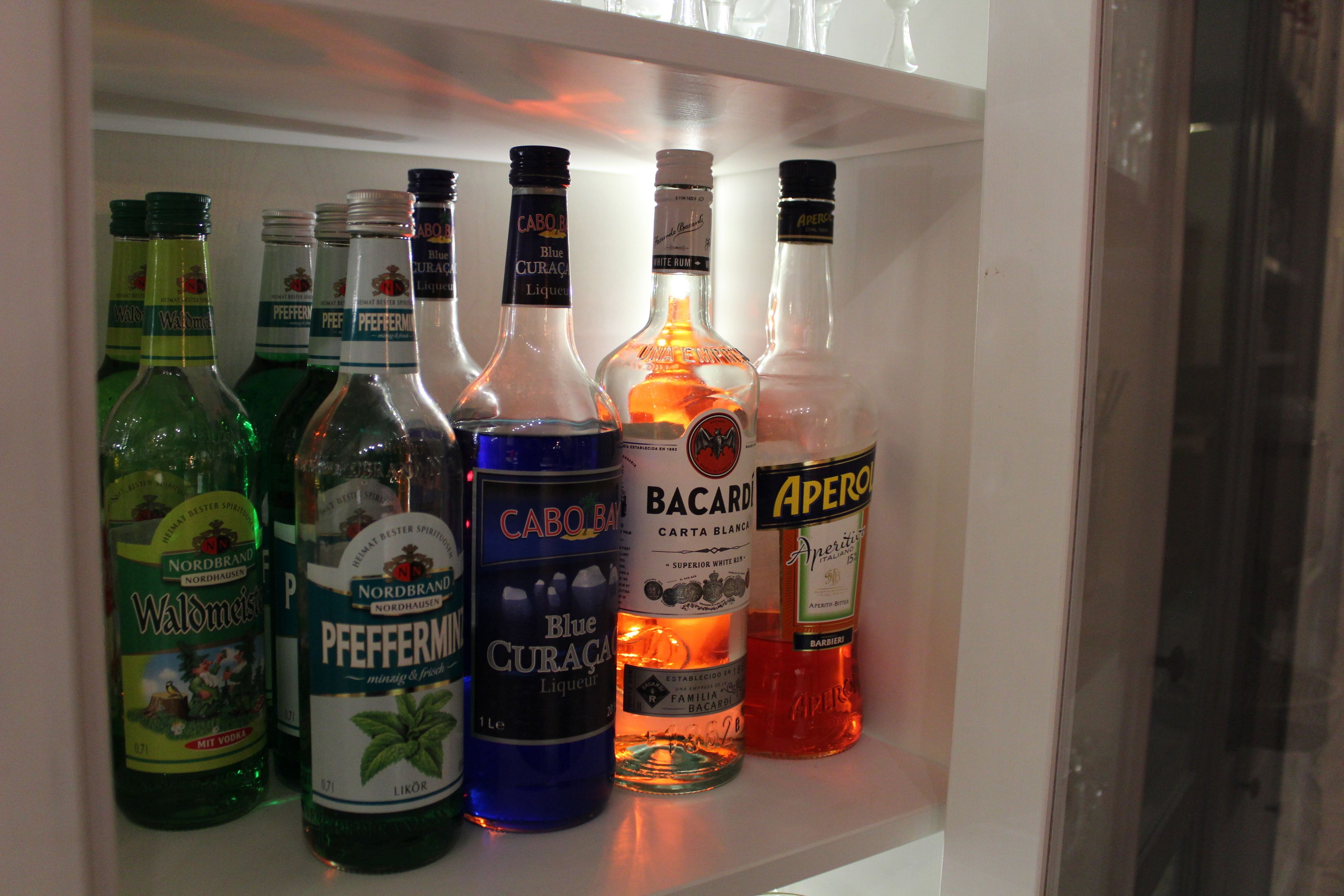Uma prateleira com diversas garrafas de bebidas alcoólicas.