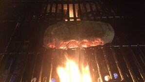 A grill with a large piece of meat being cooked over an open flame. - Gasthof Hausmann (Schluechtern)