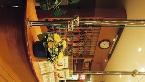 A hotel reception area with a marble wall, a clock, and a reception desk with a plant. - Hotel Panon (Hodonin)