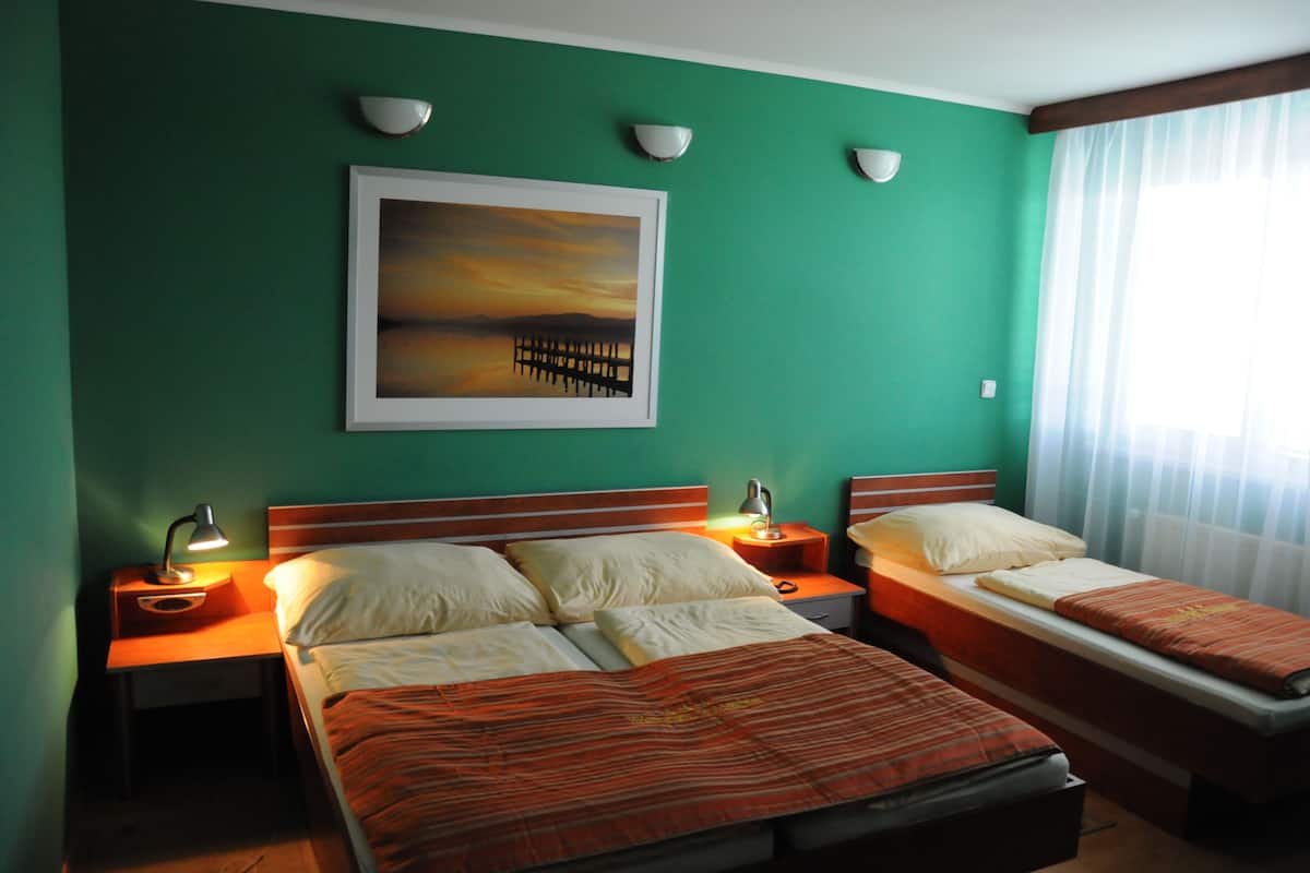Una camera d'albergo con due letti, un quadro appeso al muro e una finestra con tende.