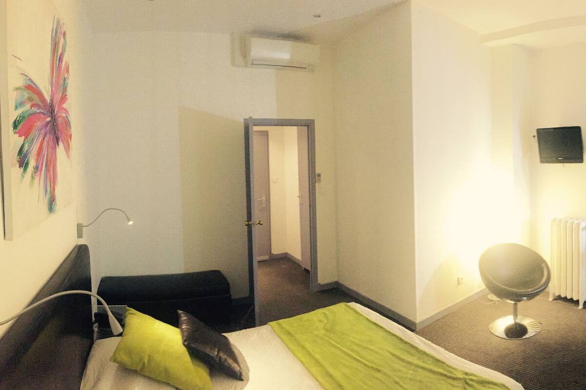 Ein Hotelzimmer mit Bett, Nachttisch, Stuhl, Spiegel und Heizkörper.