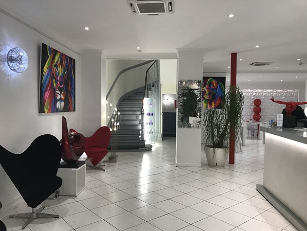 A modern interior with a staircase, a reception desk, and a colorful abstract painting. - Le Capitole (Toulouse)
