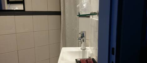 A bathroom with a white sink, a mirror, and a shower curtain.